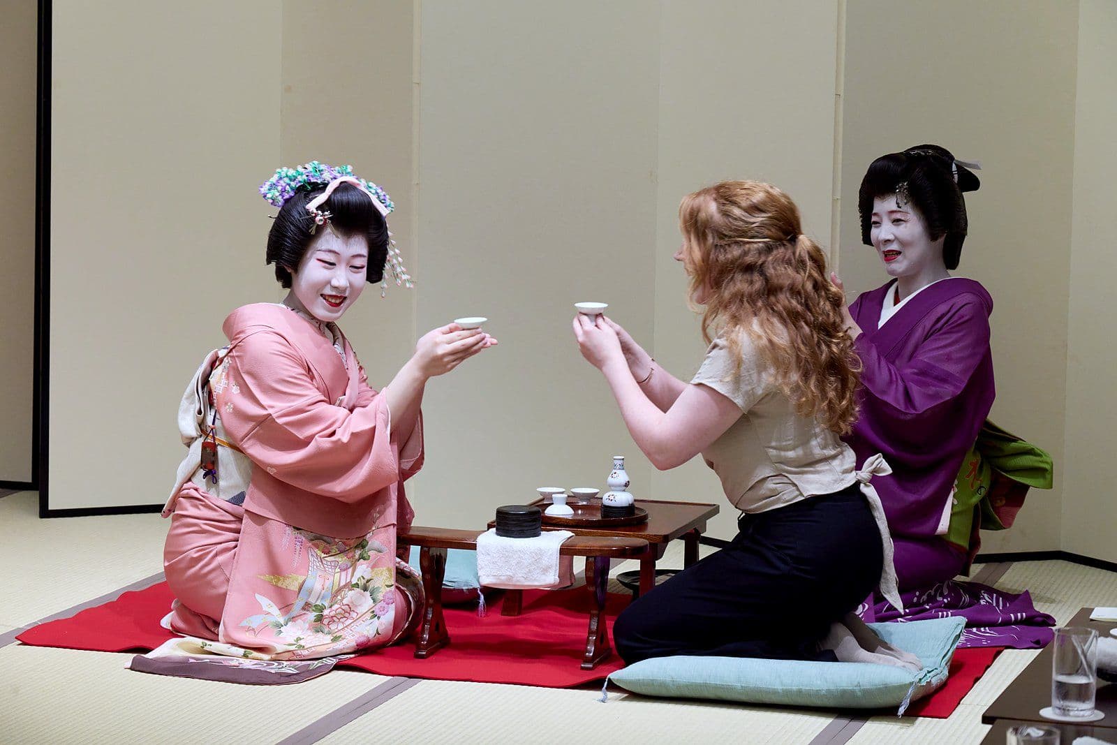 A geisha and a guest raising their cups to each other.