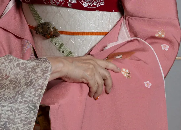 Close-up of the okami's hand on a geisha's sleeve.