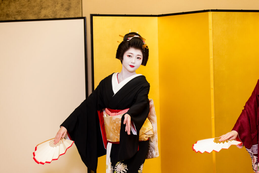 Geisha performing traditional dance with fan at ozashiki