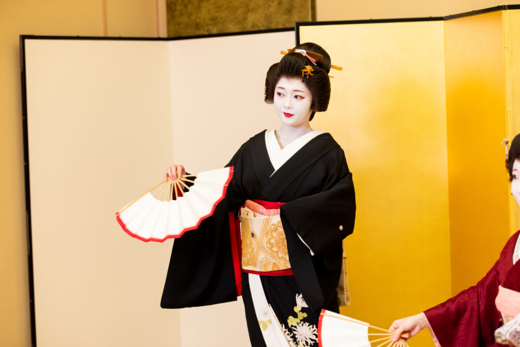Traditional geisha portrait in silk kimono with white makeup