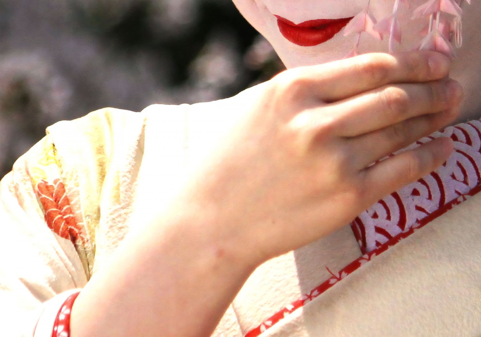 Close-up of geisha applying traditional white oshiroi makeup with a brush