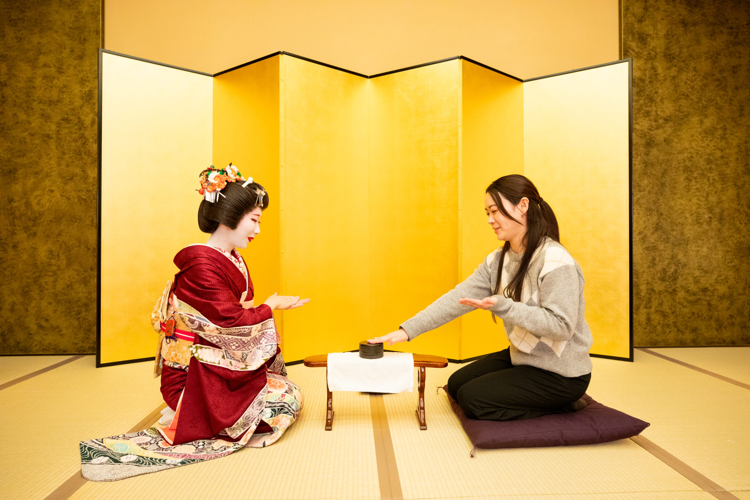 A player places an open palm on the hakama during a Konpira Fune Fune round at a Tokyo geisha tea house