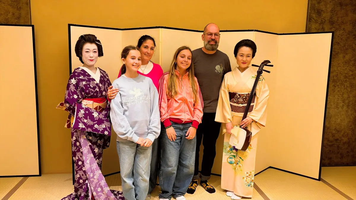 Guests taking commemorative photo with geisha in kimono at Asakusa Miyakodori