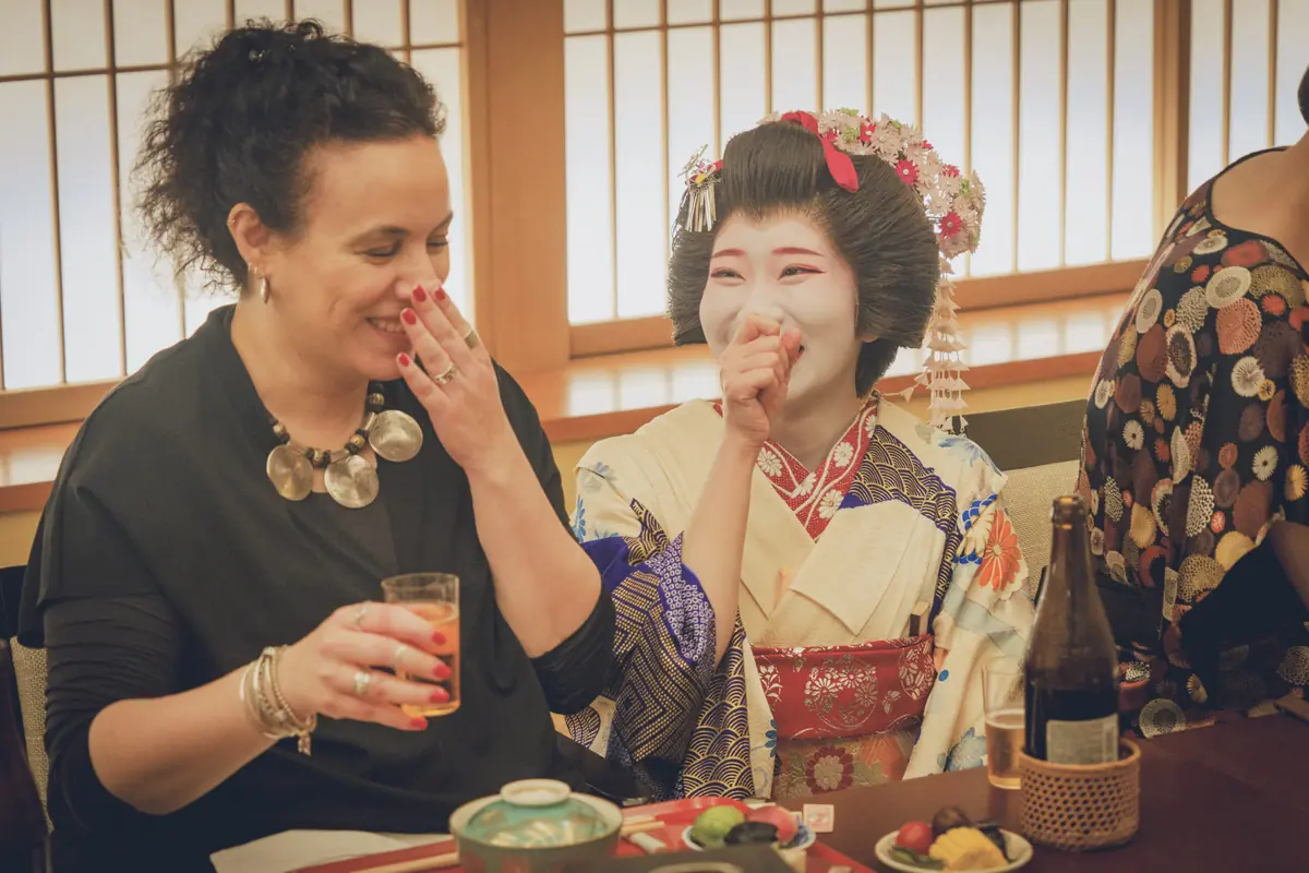 Foreign guest and hangyoku apprentice geisha sharing a laugh during conversation at Asakusa Miyakodori