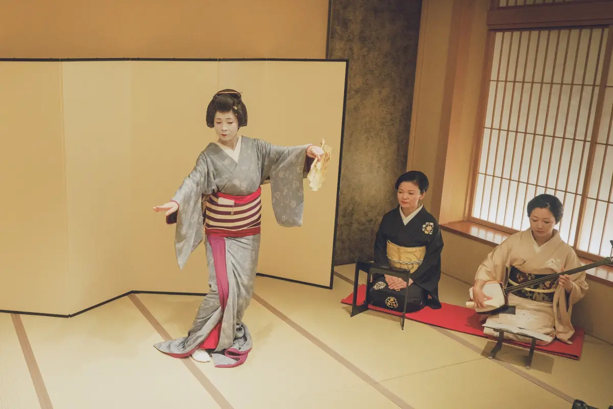 Jikata geisha playing shamisen beside tachikata geisha dancing in the tatami room