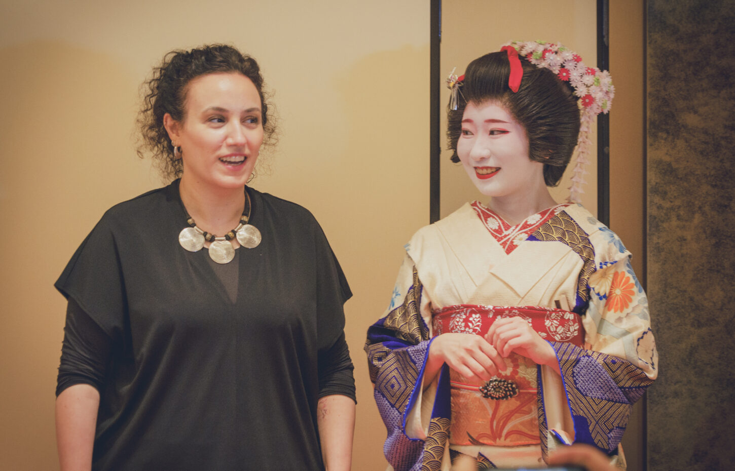 International guests sharing a warm, smiling moment with an Asakusa geisha at Miyakodori — geisha culture still very much alive today