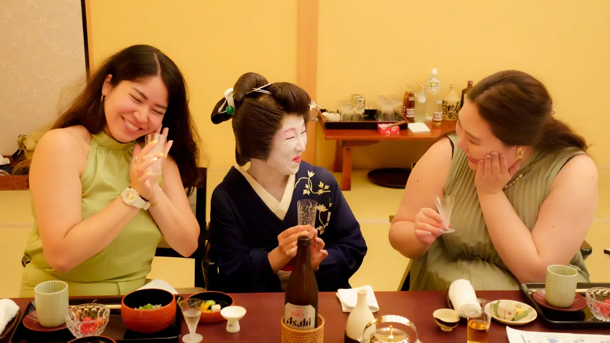 Geisha in traditional kimono greeting guests and pouring drinks at the start of an ozashiki