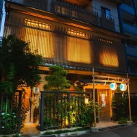 Traditional Japanese restaurant at dusk with warm orange light, wooden lattice facade, and a gated garden.