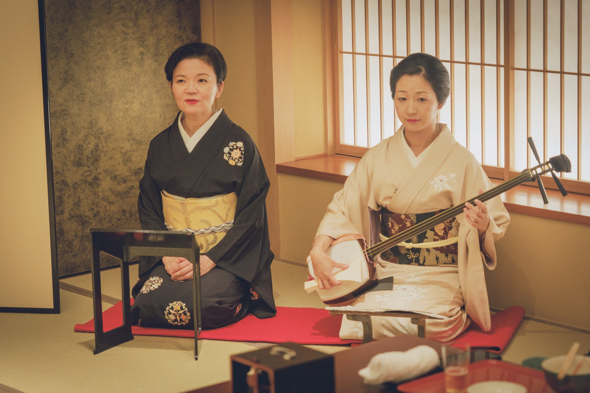 A geisha in a black five-crested formal kimono showing the left-over-right collar