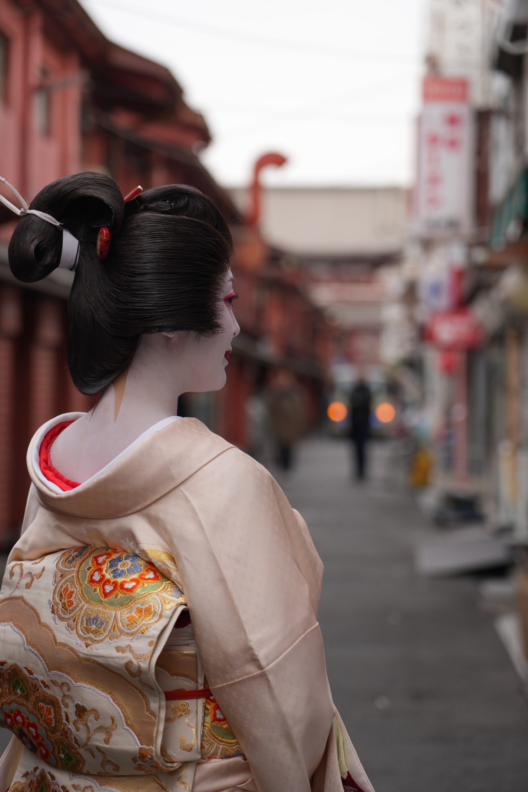 A full-length portrait of an Asakusa geisha in a pale pink kimono