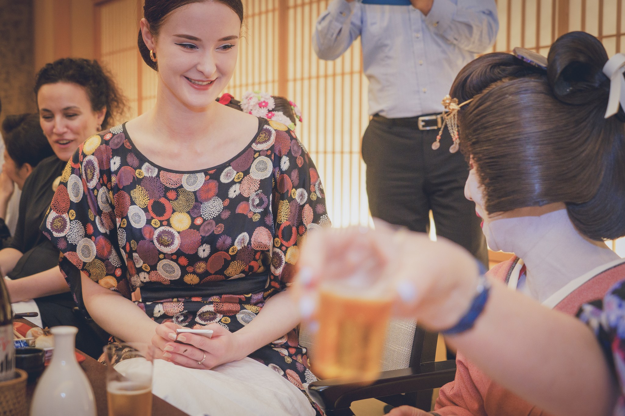 A geisha pouring drinks for international guests at an ozashiki banquet