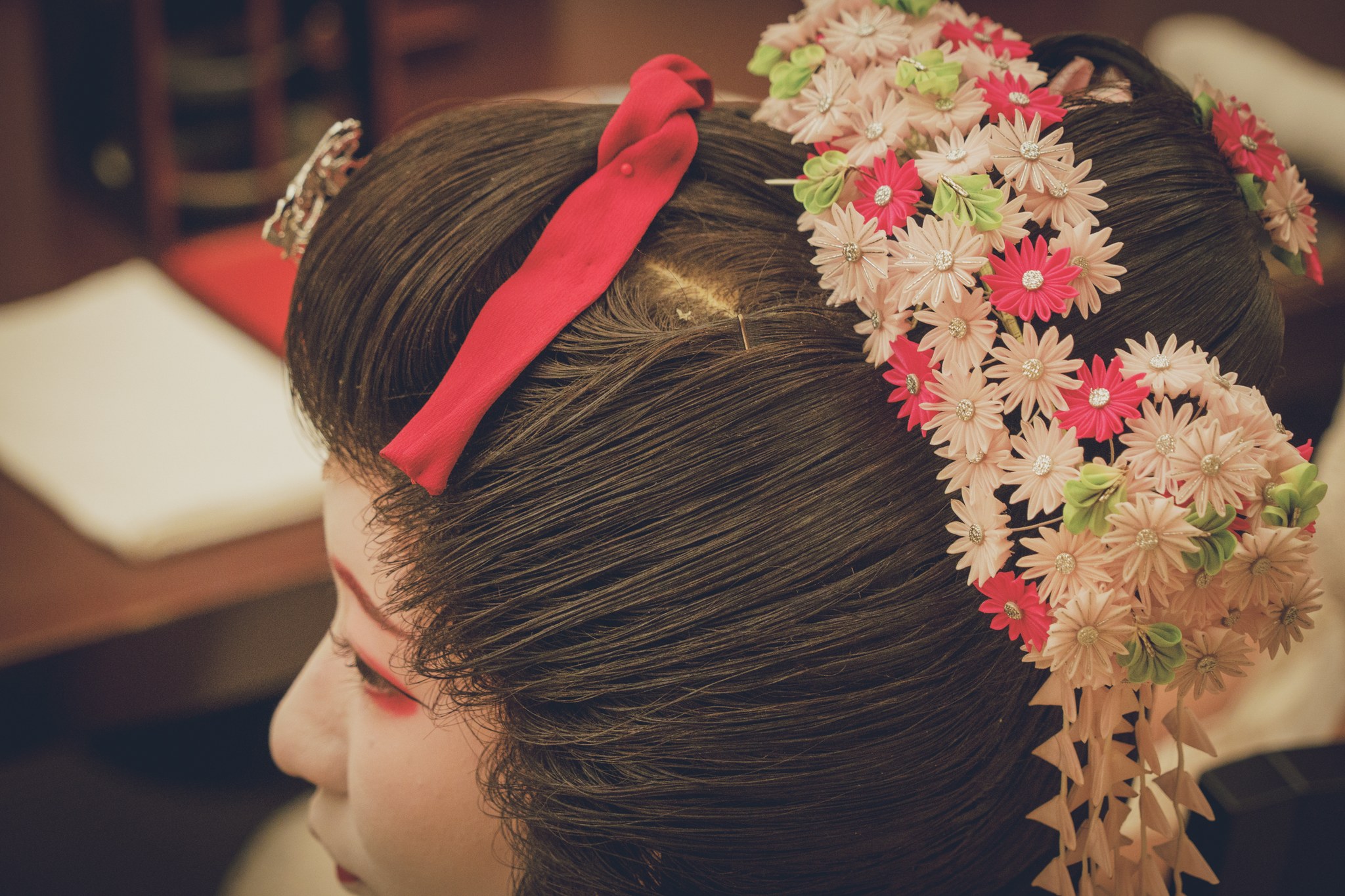 Close-up profile of a geisha wearing hana kanzashi with cascading silk flowers