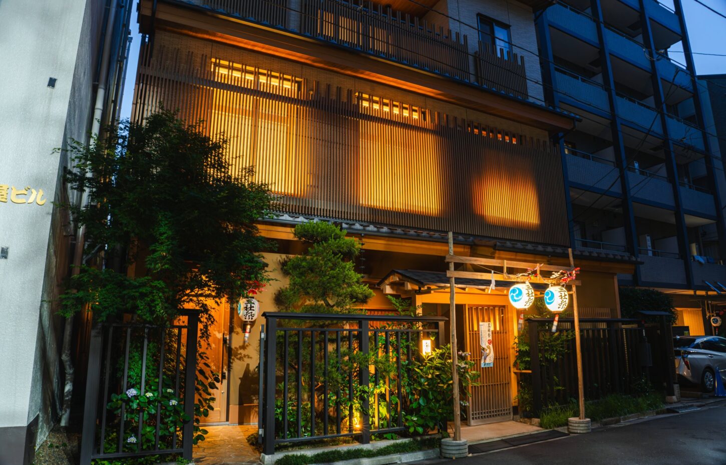 A hanamachi (geisha district) lane in Asakusa at dusk, with wooden lattice fronts and lanterns