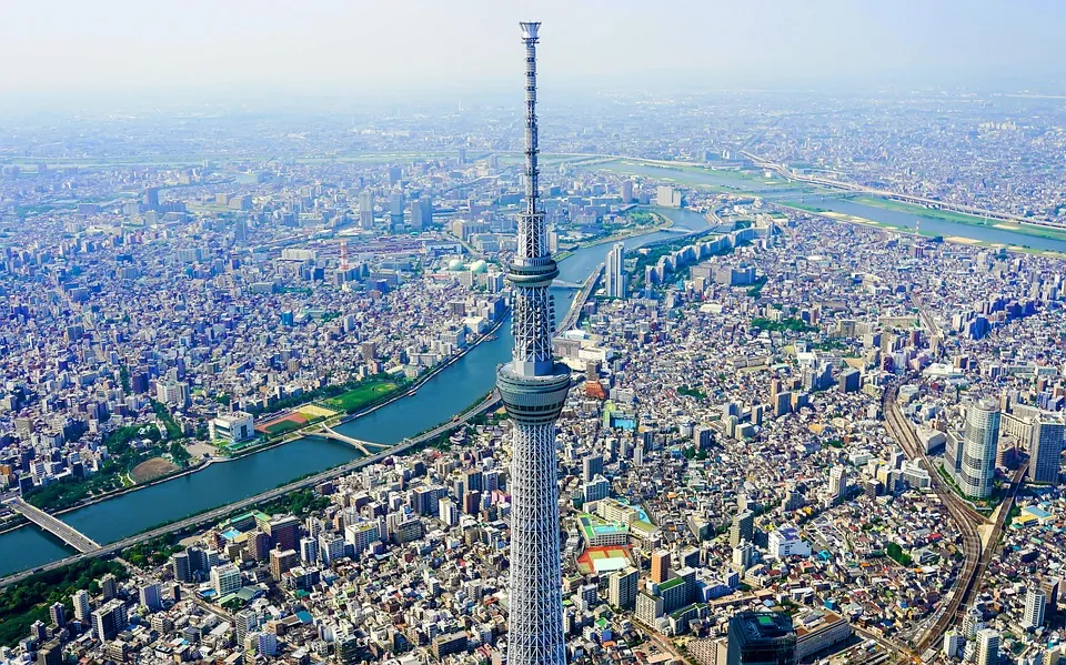 Aerial view of Tokyo Skytree towering over a dense city with a river winding through the urban landscape.