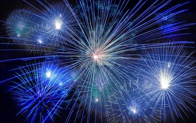 Fireworks exploding in a dark sky with blue and white bursts of light.
