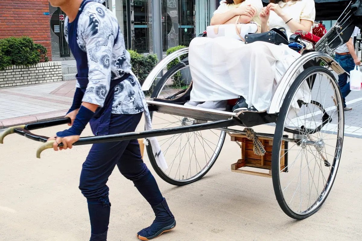 Rickshaw (jinrikisha) driver pulling tourists through the historic backstreets of Asakusa near Senso-ji Temple