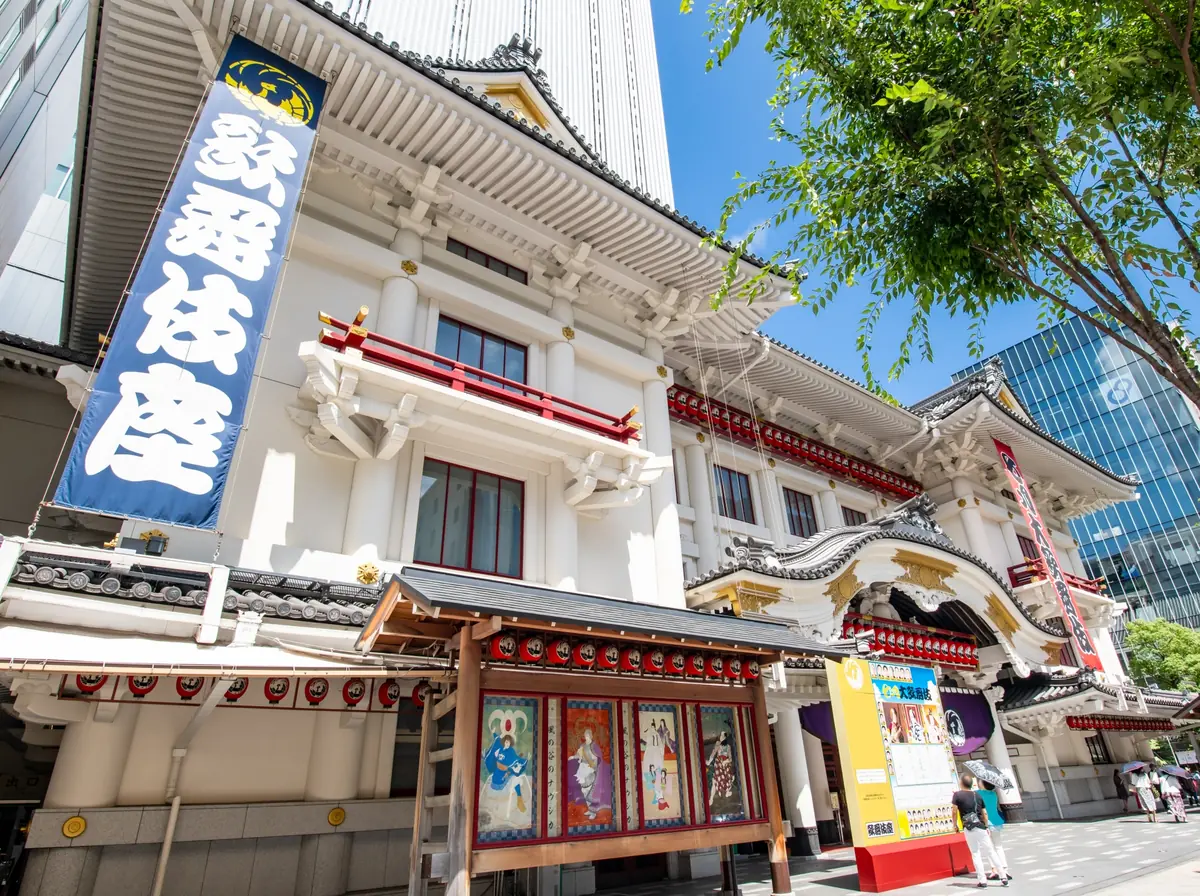 Traditional-style theater entrance with ornate curved roof, red accents, and a tall blue banner with white characters.