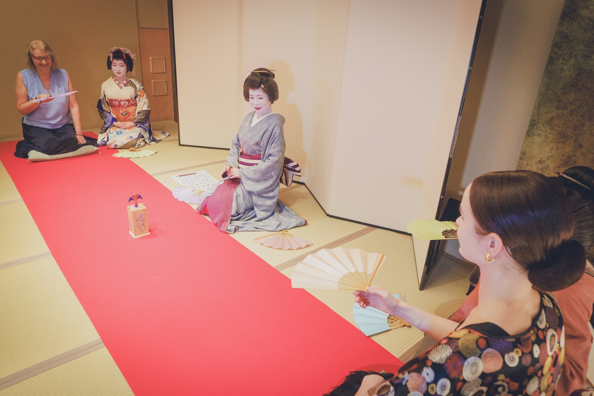 A guest tossing a folding fan toward the butterfly-shaped tosenkyo target at a Miyakodori ozashiki — the most literary of the three ozashiki games