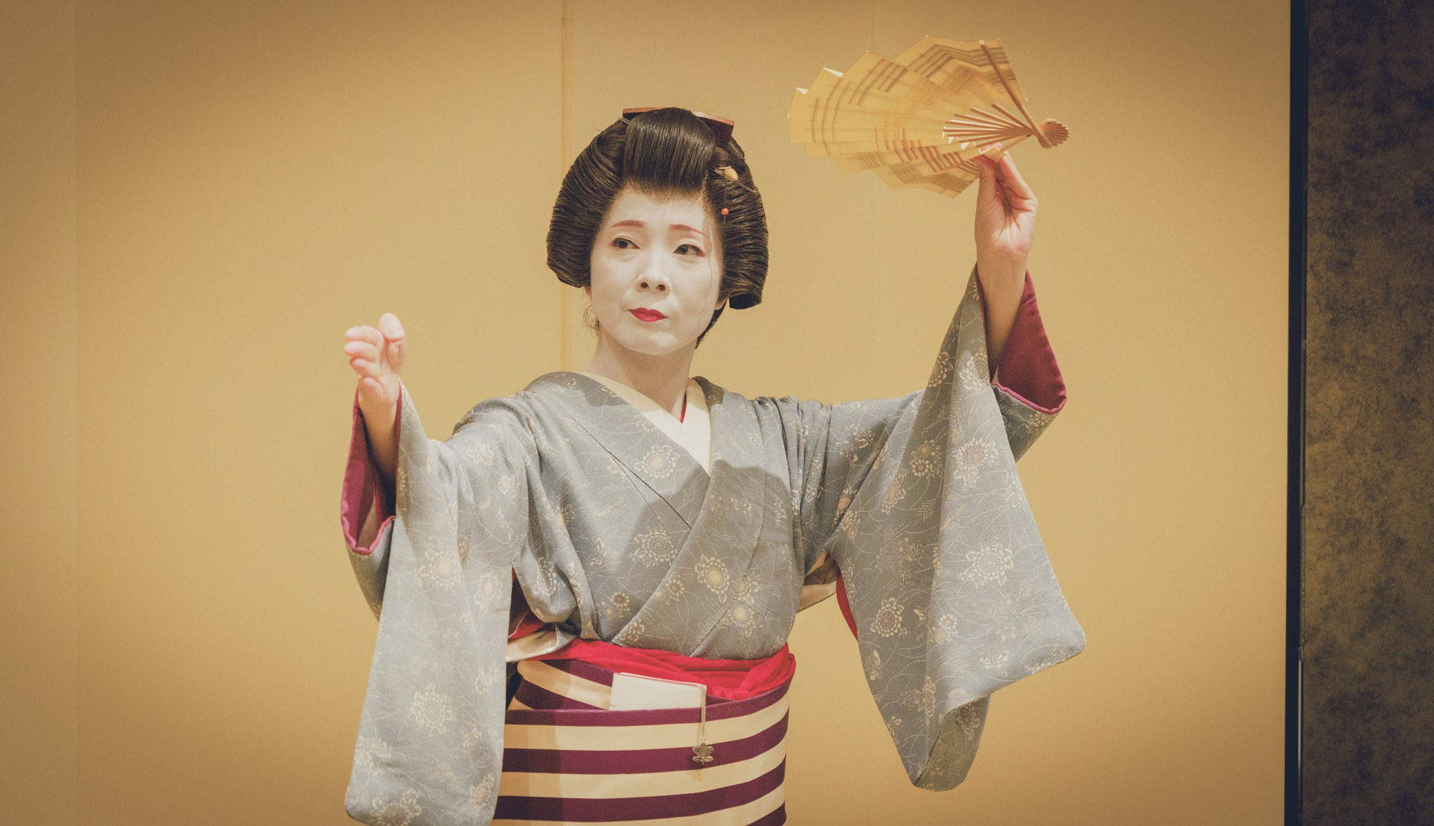 A Tokyo tachikata geisha in formal white makeup performing a fan dance