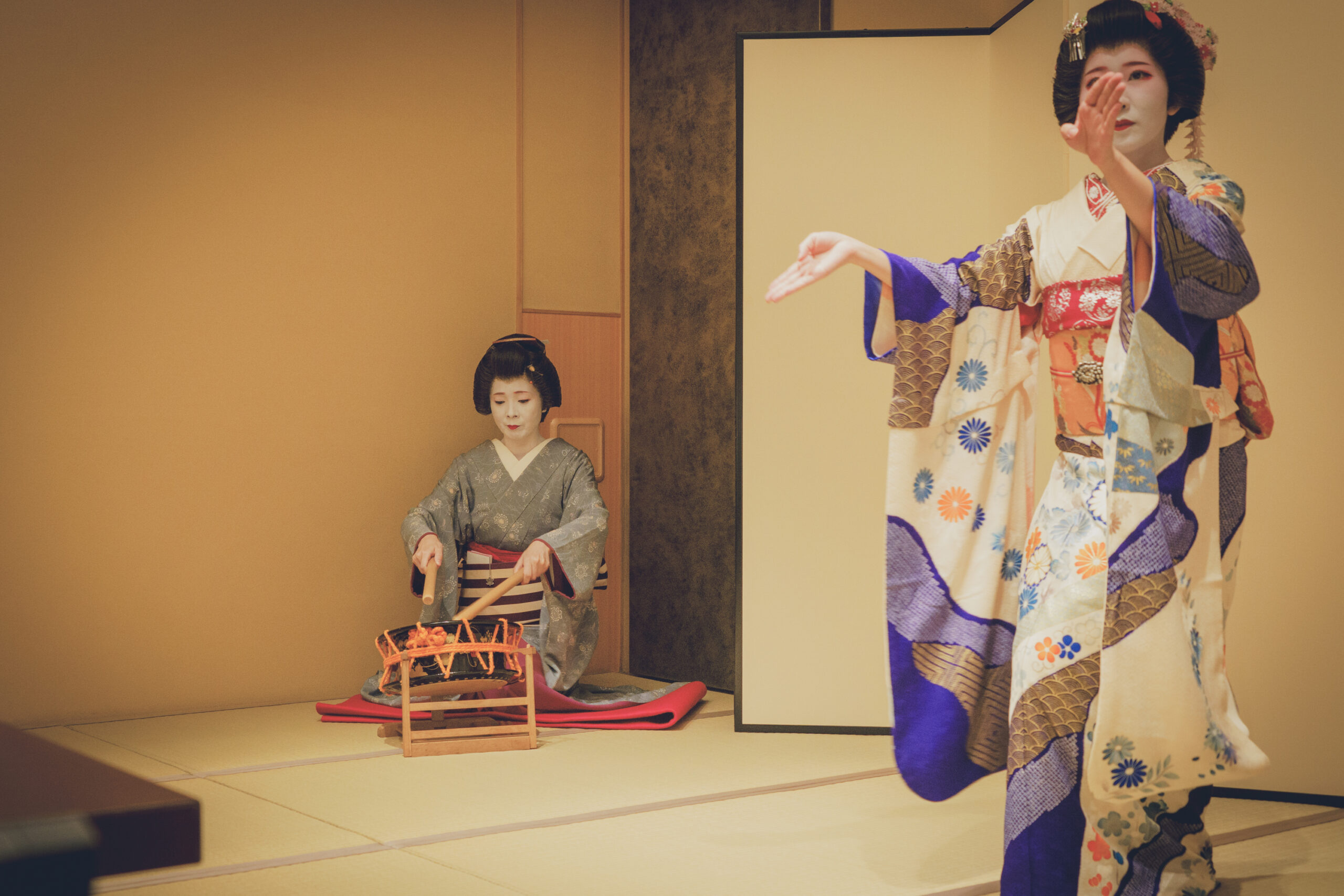 Two Asakusa geisha performing together — one dancing to the other's music — at a private ozashiki, the living art performed an arm's length away