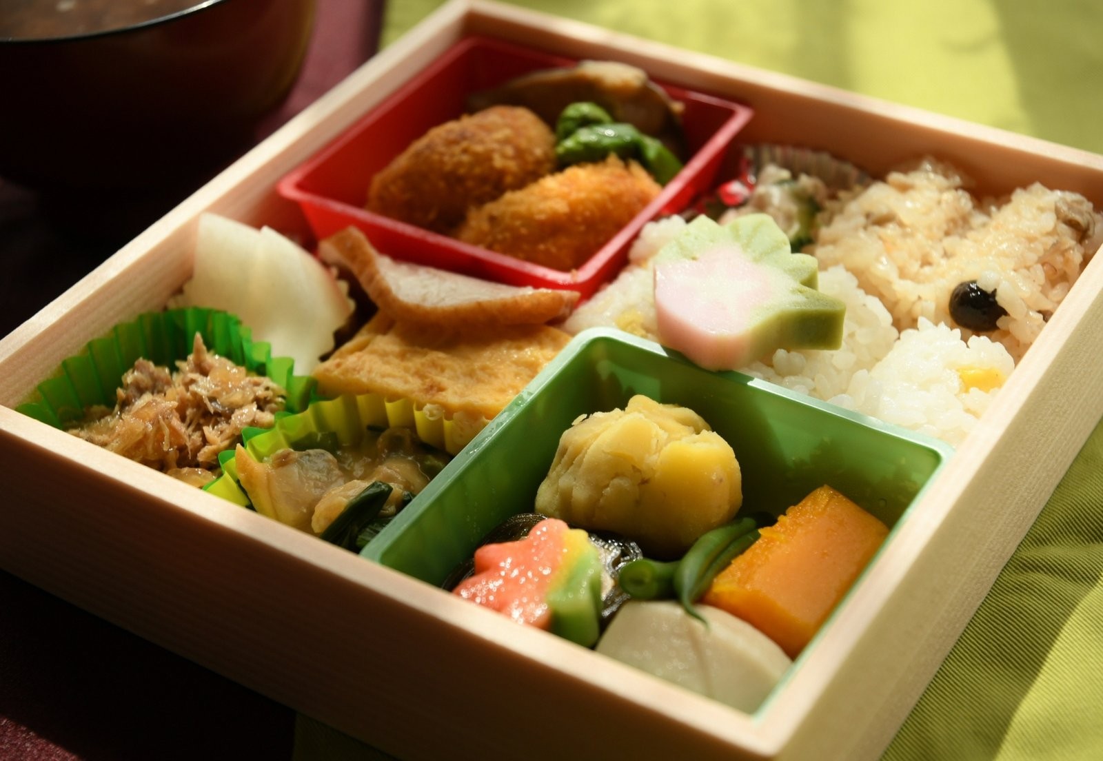 Wooden bento box with rice, seasonal vegetables and small dishes