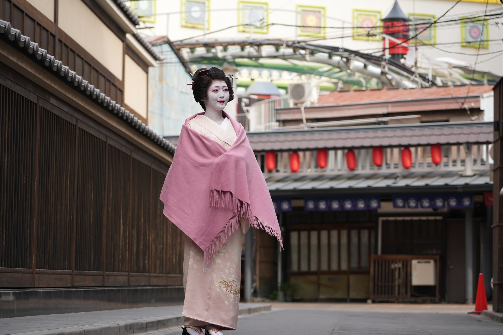 An Asakusa geisha walking a lantern-lit street in Asakusa at dusk