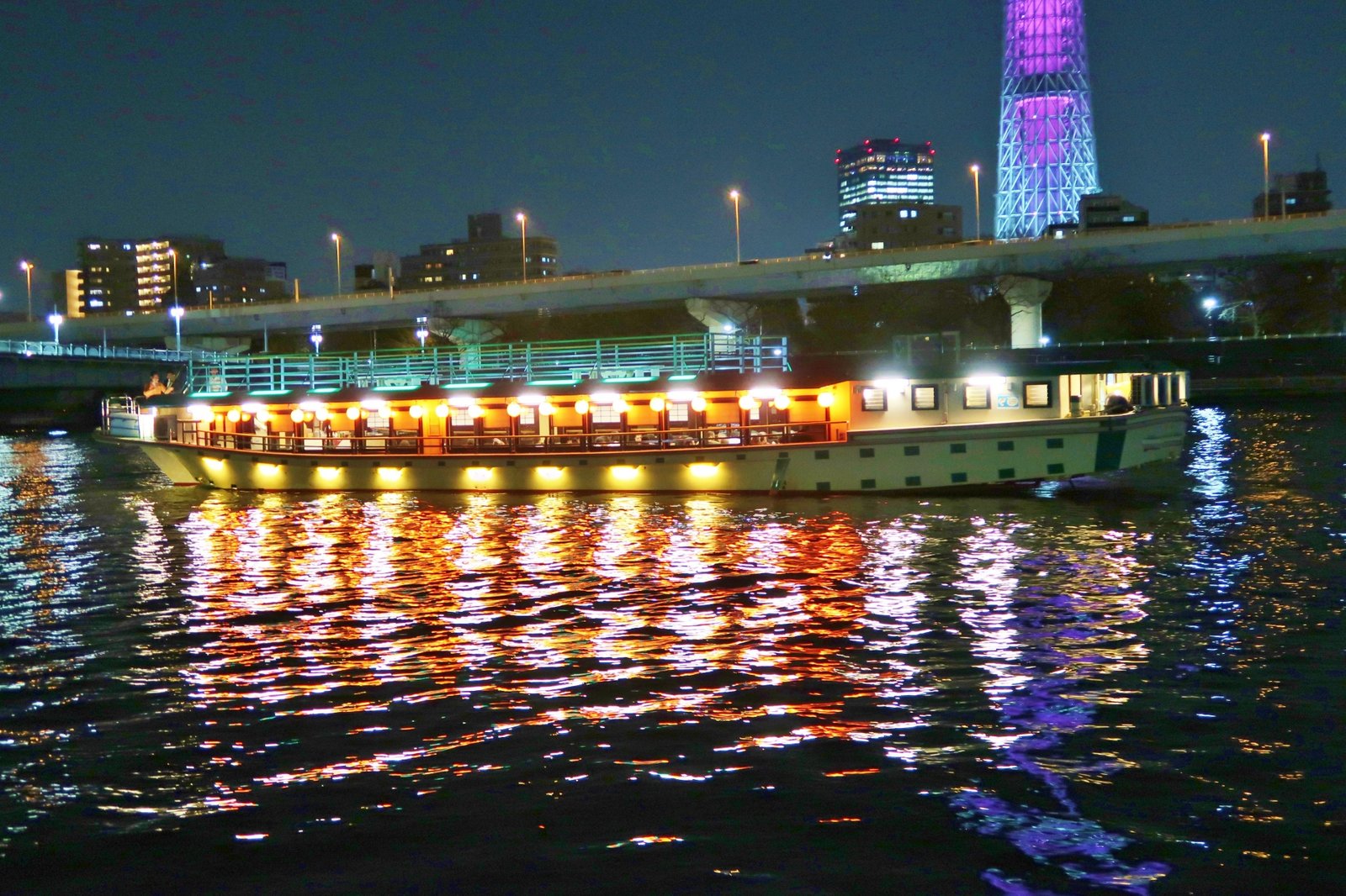 A lantern-lit boat on the Sumida River, its light reflected on the water