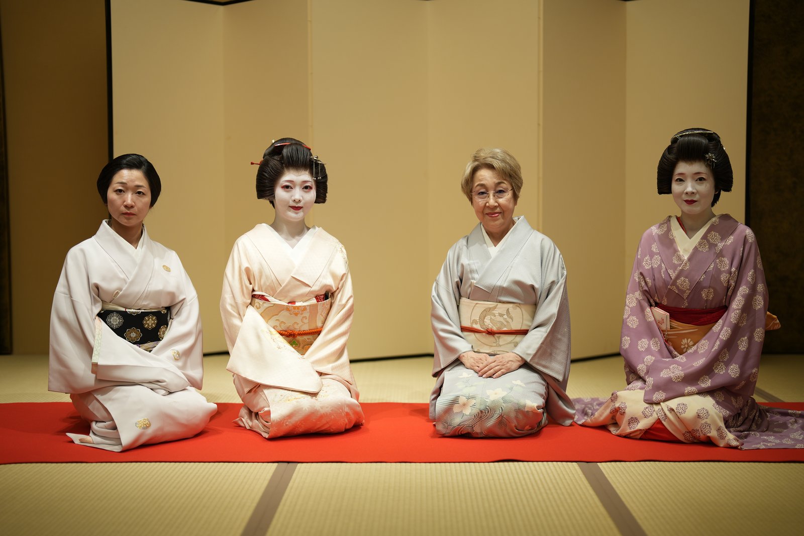 Three Asakusa geisha, one of them a hangyoku, seated with the okami of Miyakodori in a tatami room