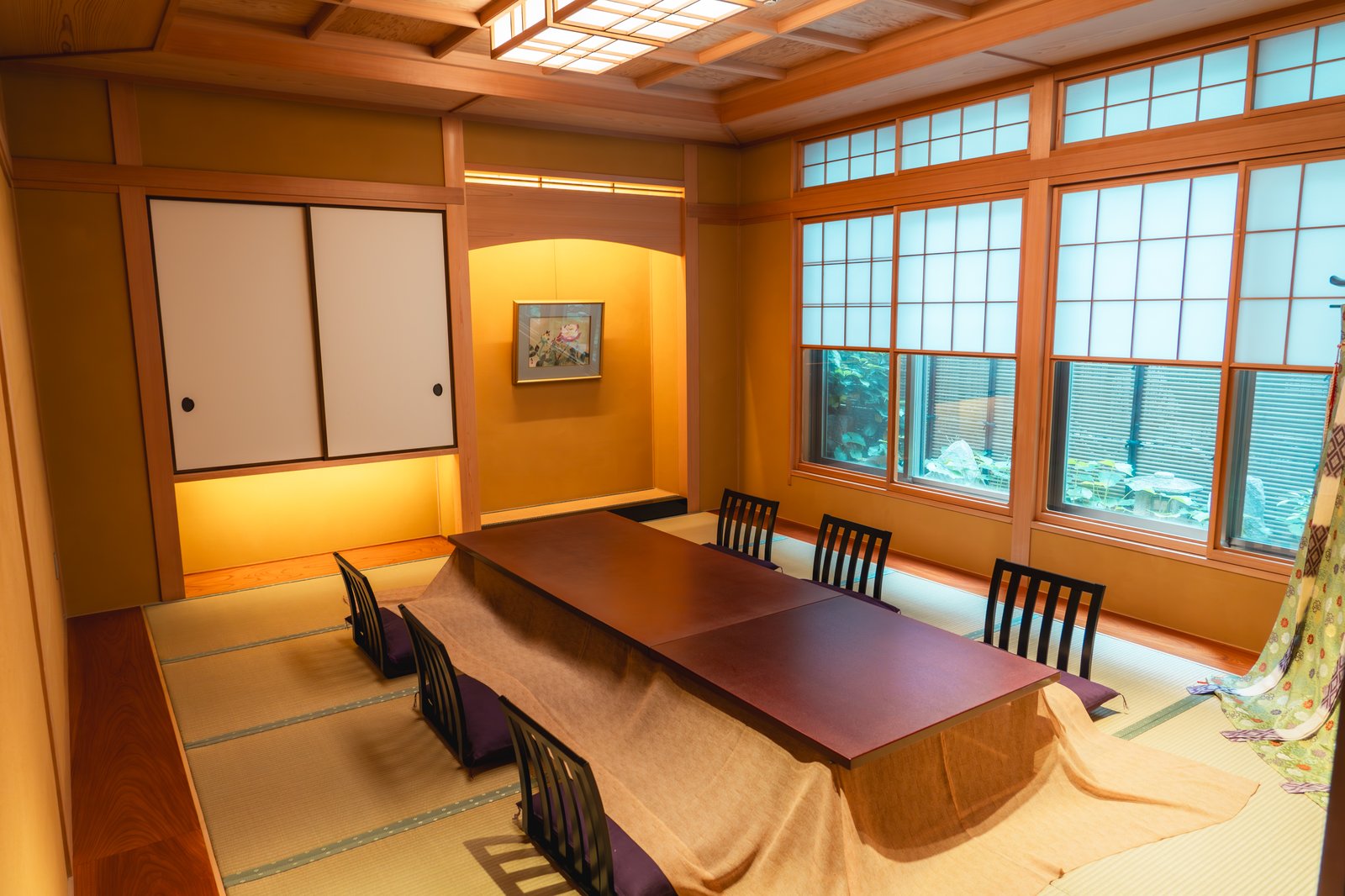 A private tatami room at Miyakodori set for an ozashiki, with a low lacquered table, floor seats on cushions, and a garden beyond the shoji