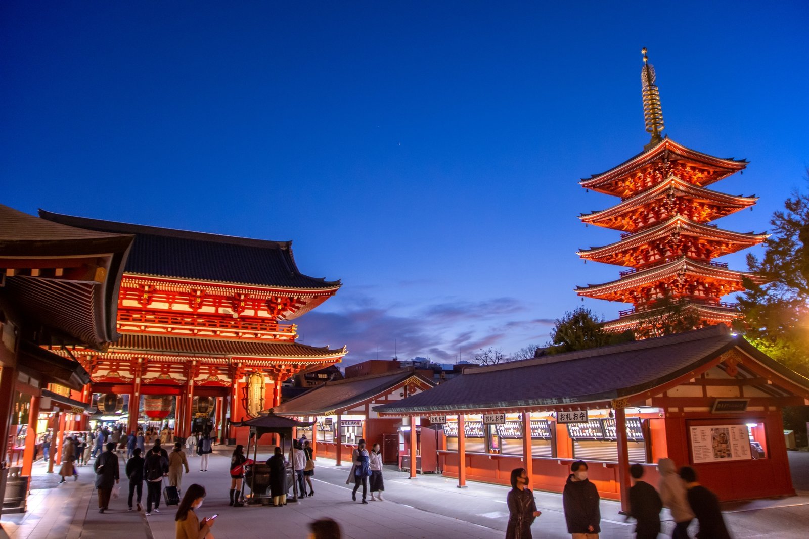The five-storied pagoda and Hozomon gate of Senso-ji glowing at dusk under a deep autumn-blue sky