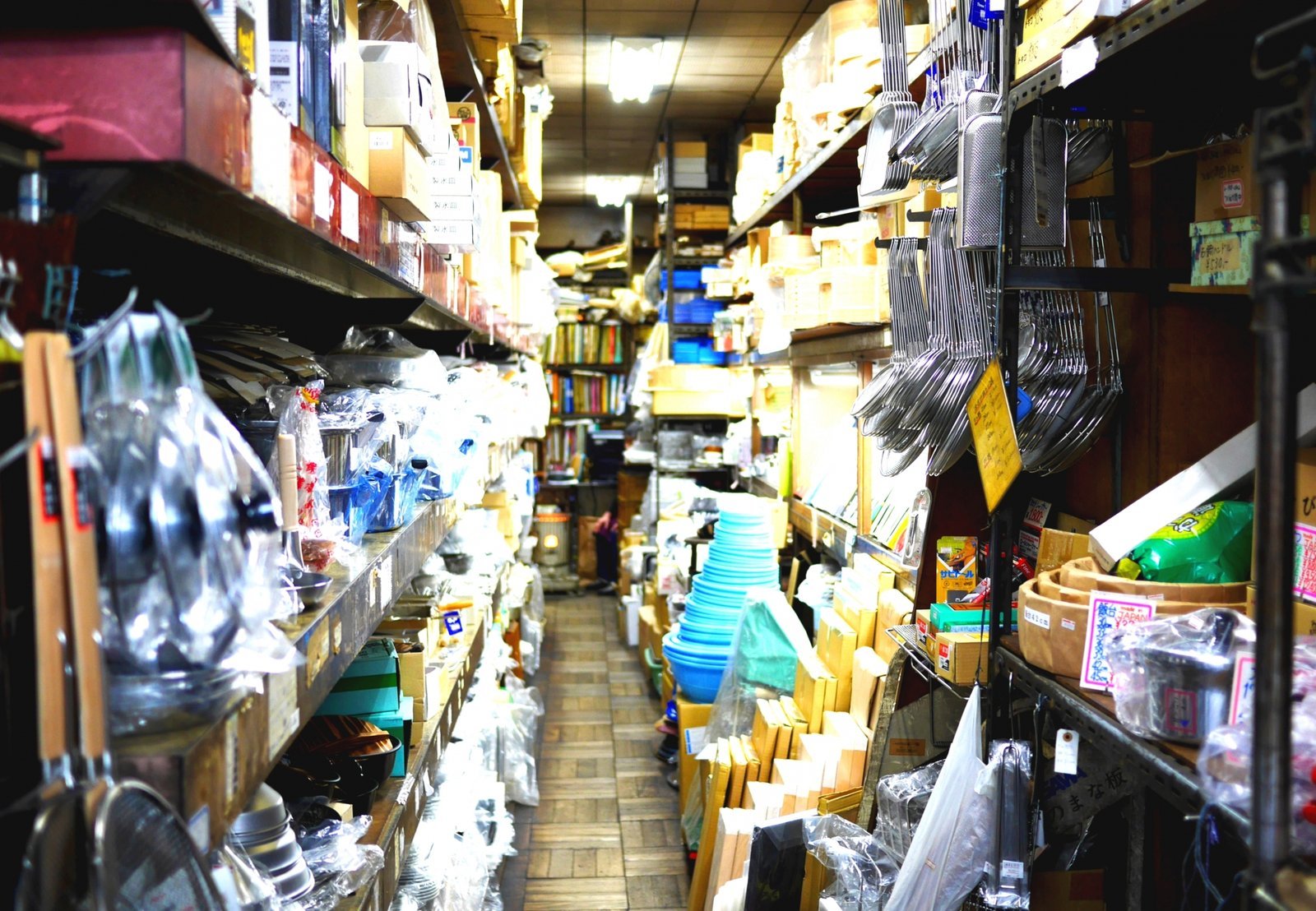A kitchenware shop on Kappabashi in Asakusa, its narrow aisle stacked with pots, strainers and tableware for restaurant kitchens