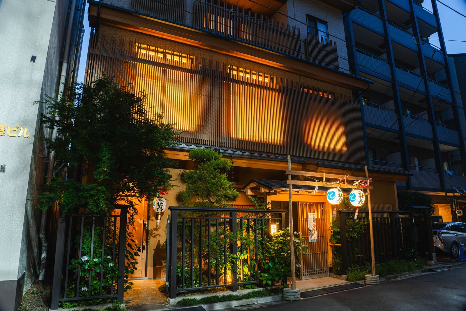 The exterior of Miyakodori, a machiai-chaya in Asakusa's hanamachi, its lanterns and lattice windows lit at dusk