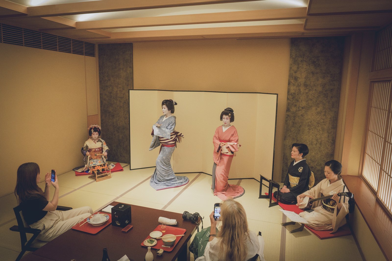 Asakusa geisha dancing to live shamisen in a tatami room at Miyakodori during a private ozashiki, with guests seated at the same low table