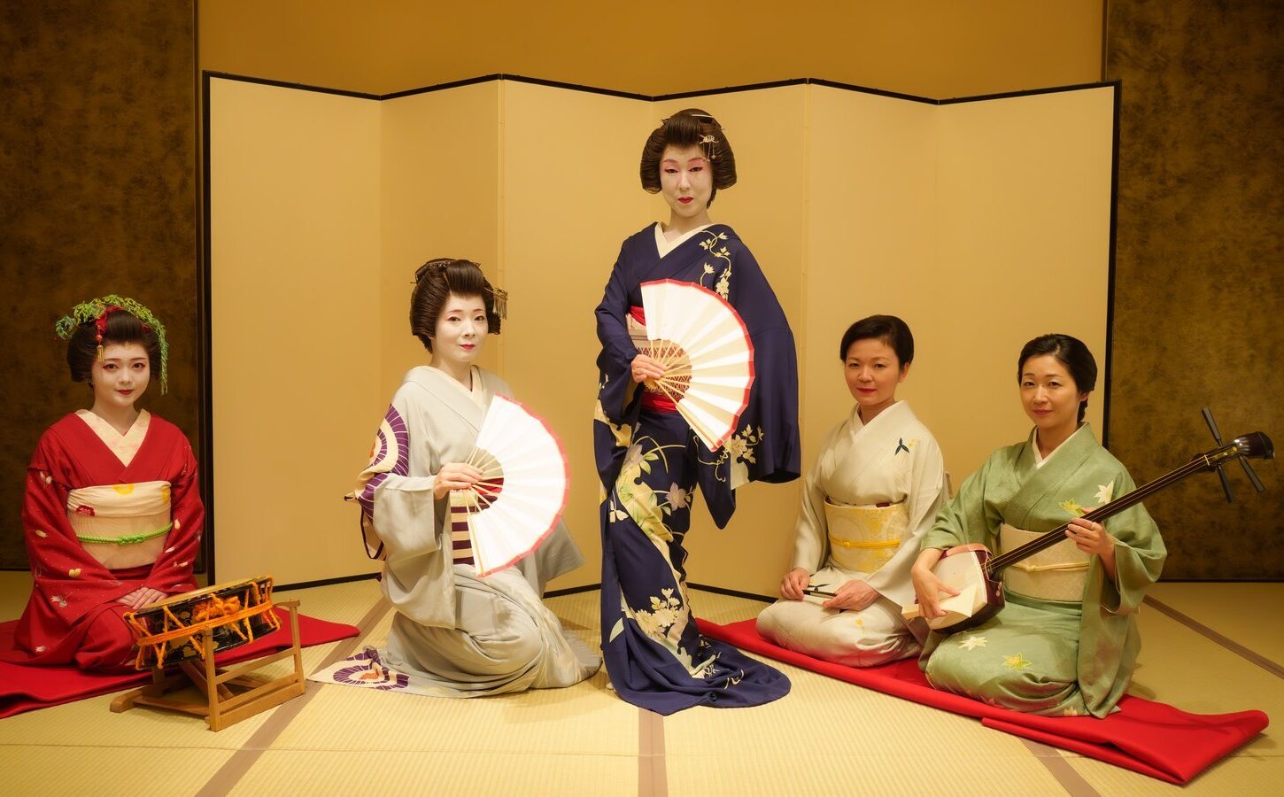 Five Asakusa geisha in formal kimono with shamisen, fan and hayashi percussion in the tatami room at Miyakodori