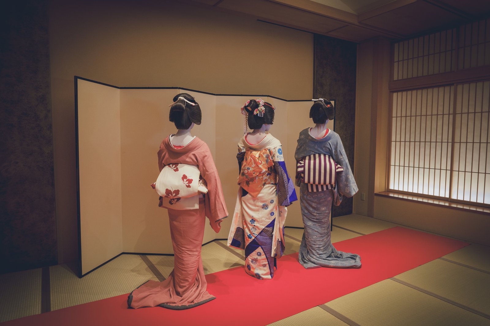 Three Asakusa geisha seen from behind, their obi sashes knotted at the back