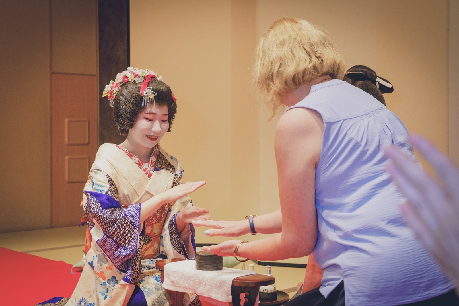 A guest and a geisha playing konpira fune fune, the fast rhythm game, at the low table during an ozashiki