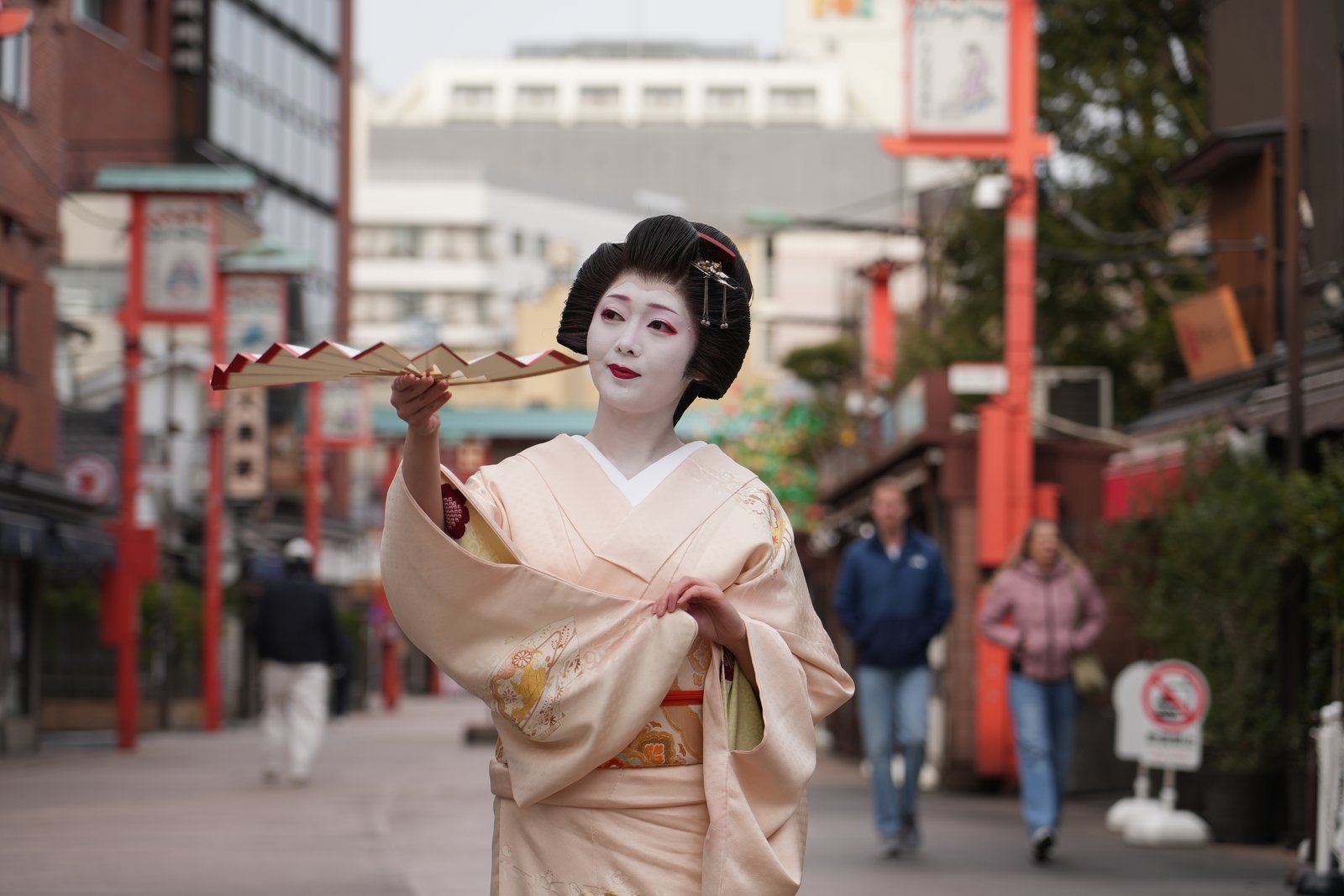Asakusa geisha performing a seasonal dance on a stage at a public showcase, watched from audience seating