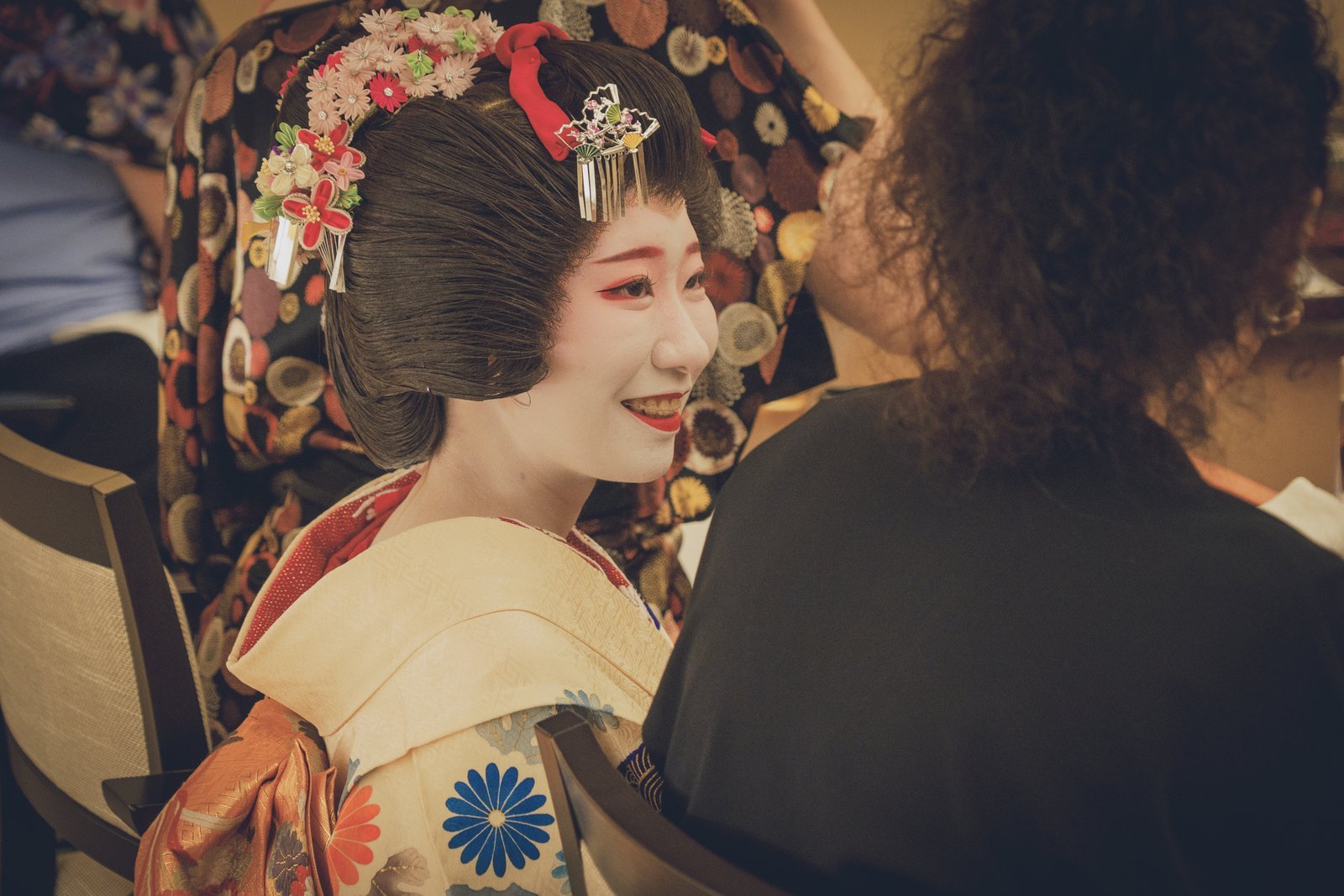 A guest and a geisha in relaxed conversation across the low table of a private tatami room