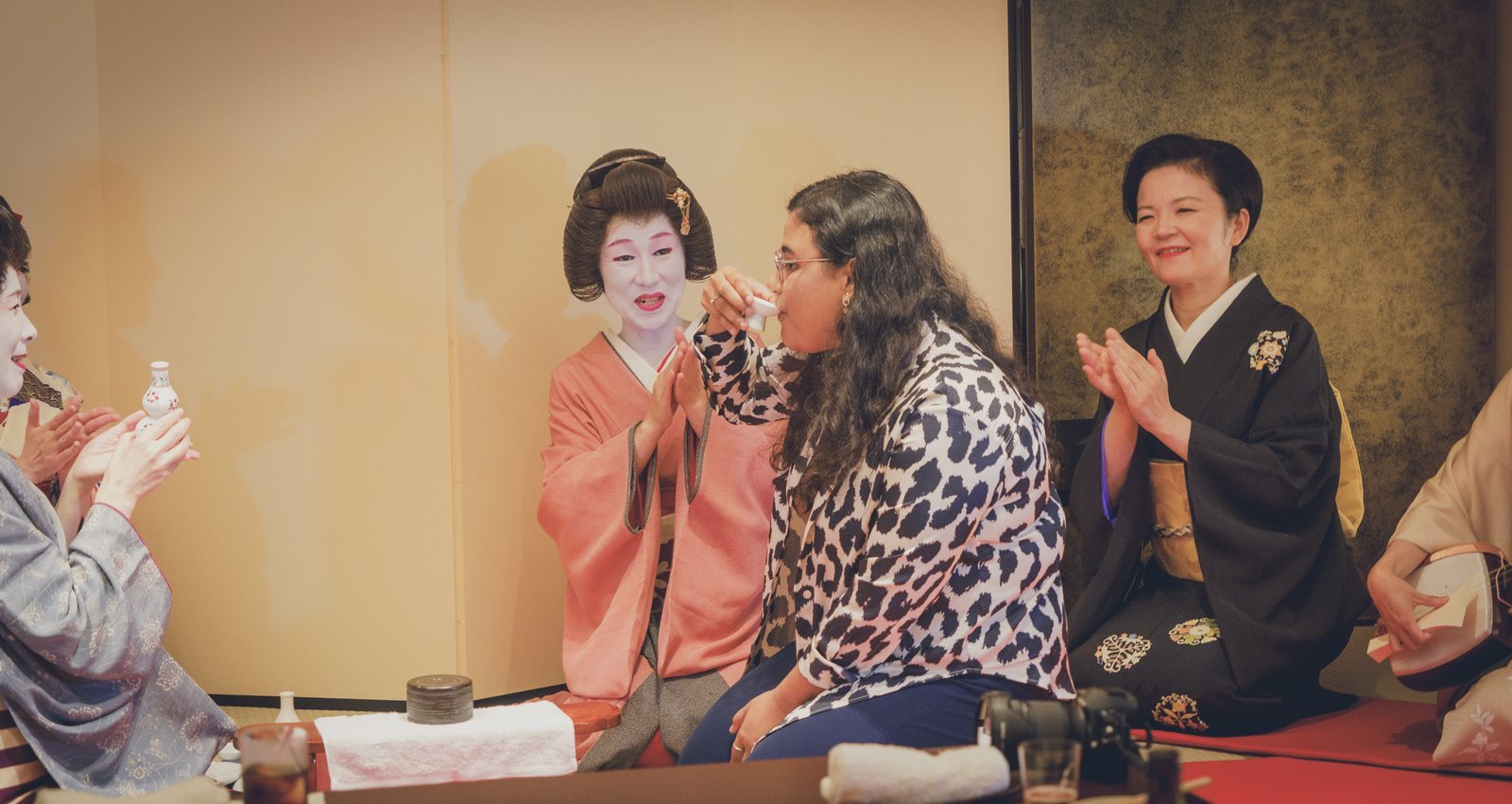 Guests and a geisha playing konpira fune fune, a traditional ozashiki game, during a group dinner