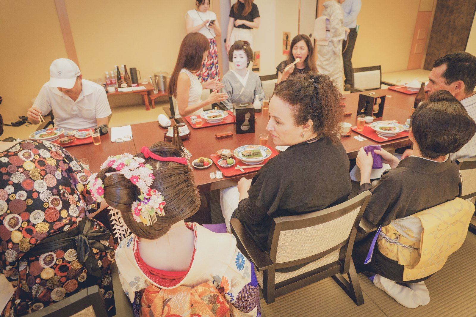 Guests seated on cushions at a low table in a tatami-matted ozashiki parlor room