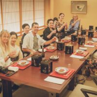 Guests raising a toast with an Asakusa geisha and the okami during a private ozashiki at Miyakodori