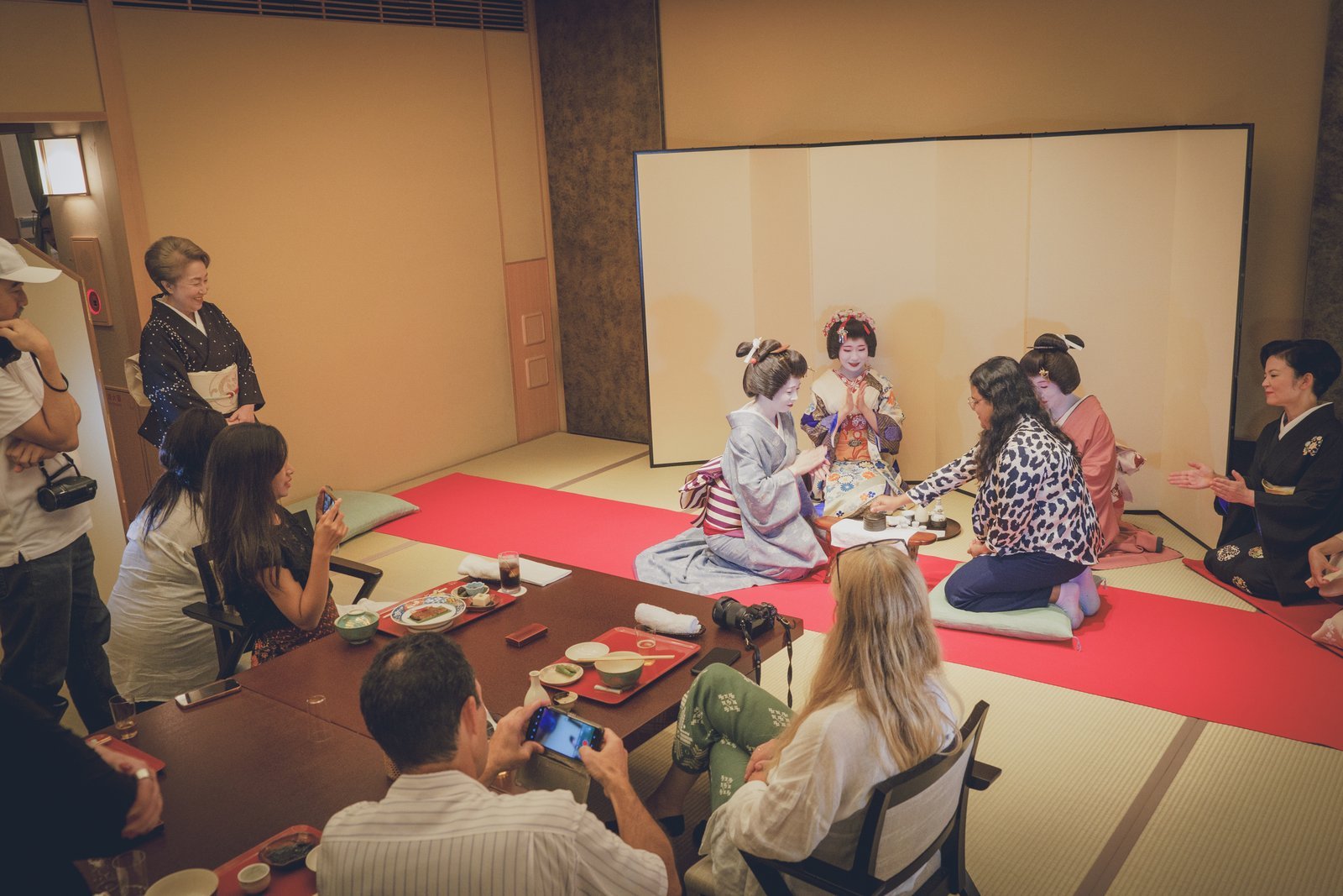 Geisha and guests playing Konpira Fune Fune around a low table during an ozashiki