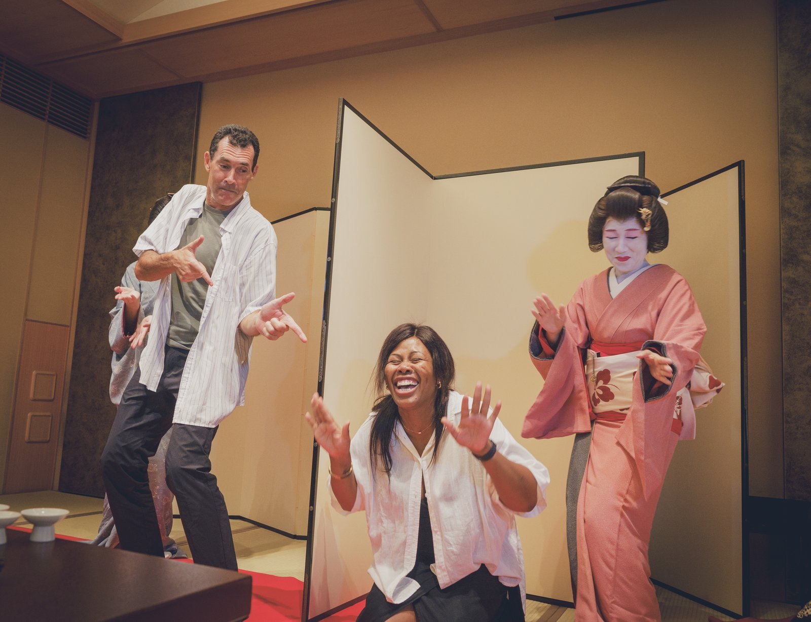 Two players striking their poses on either side of a folding byobu screen during a round of the tora tora game at Miyakodori