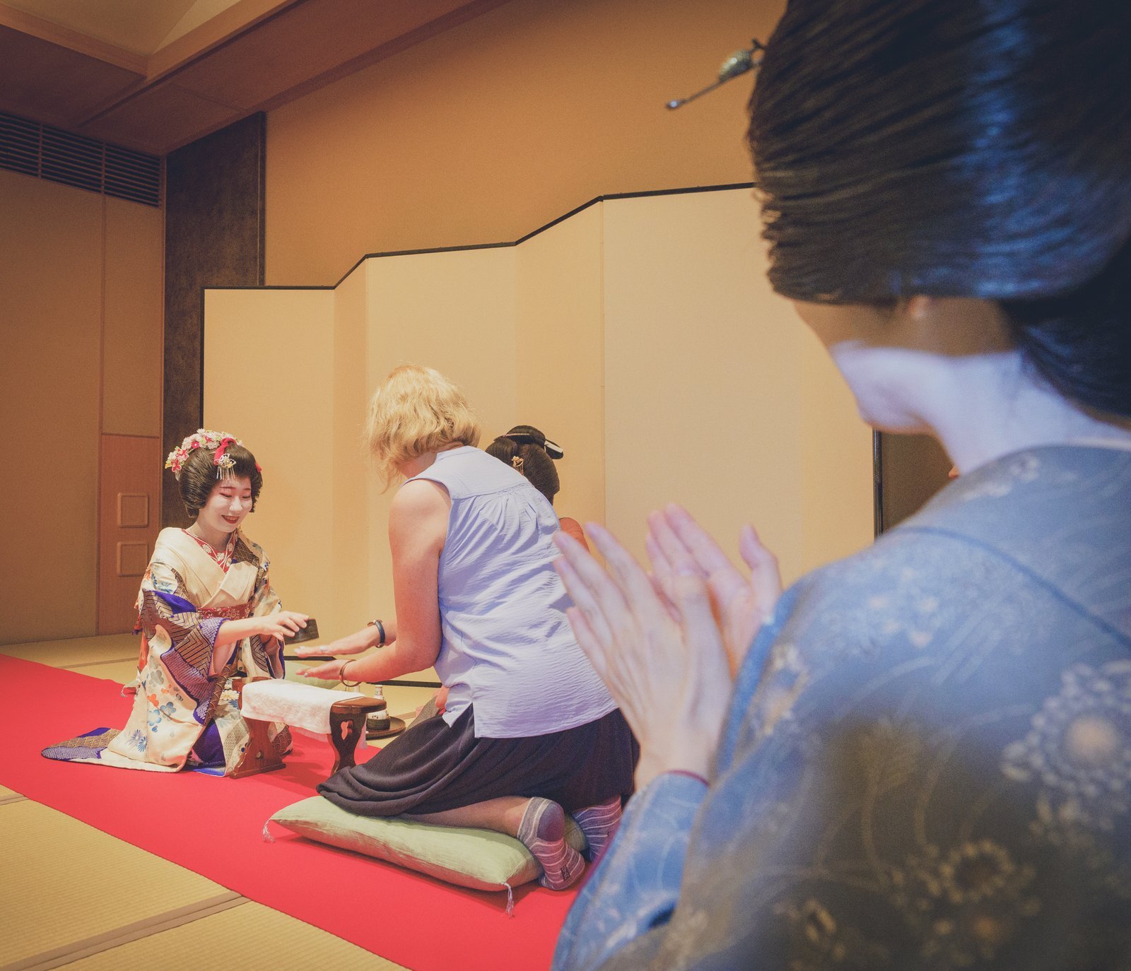 A hangyoku walking a first-time guest through an ozashiki parlour game before the round begins