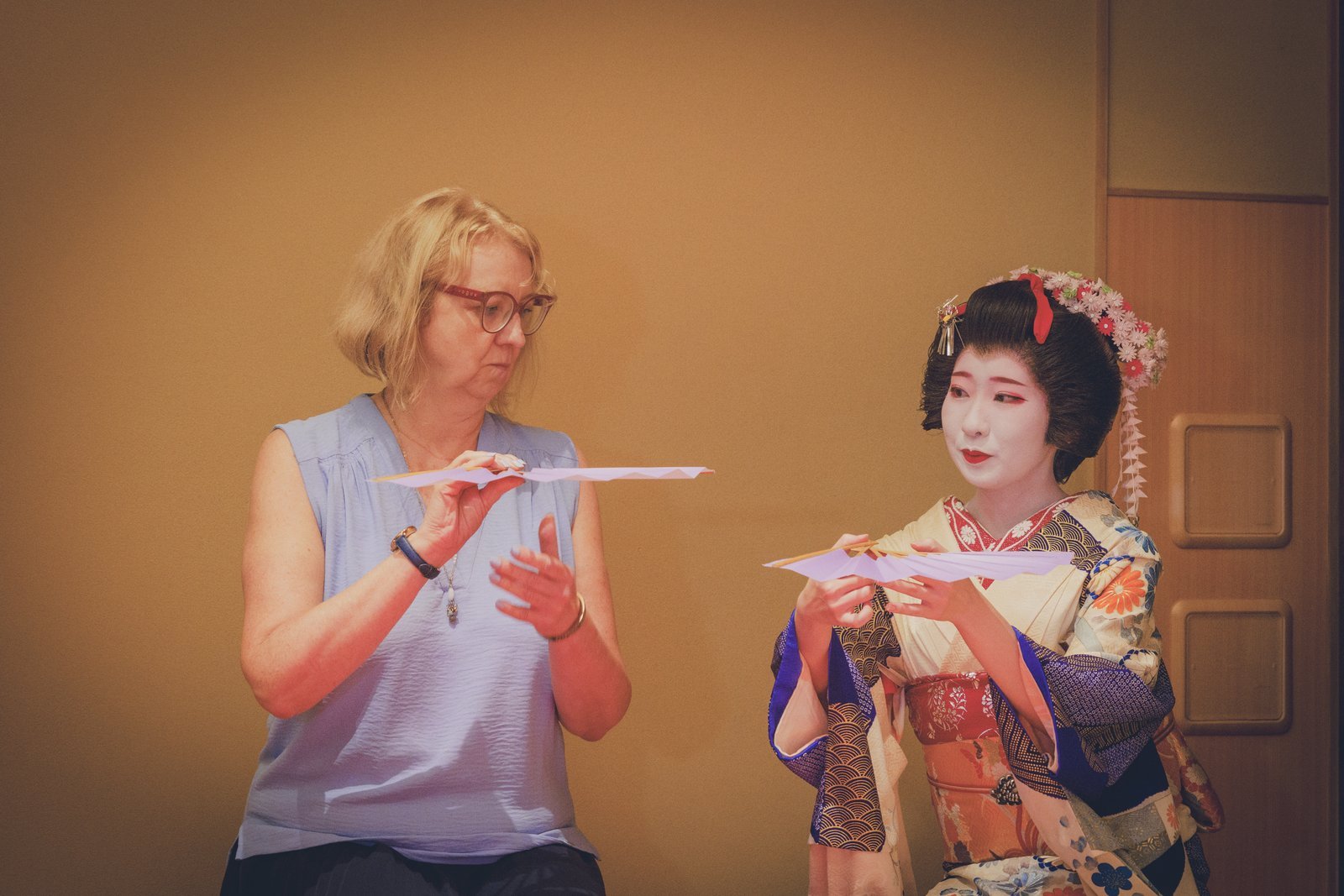 A geisha showing a first-time guest how to hold the tosenkyo fan during a private ozashiki plan at Miyakodori