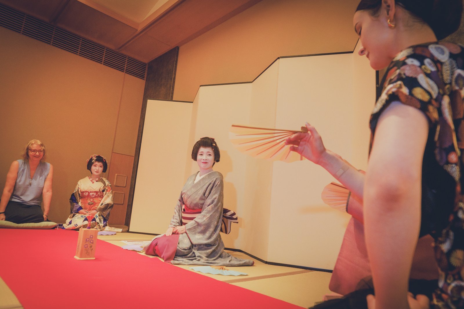 Guests and geisha playing tosenkyo together at a private Miyakodori ozashiki, a guest taking aim with her fan