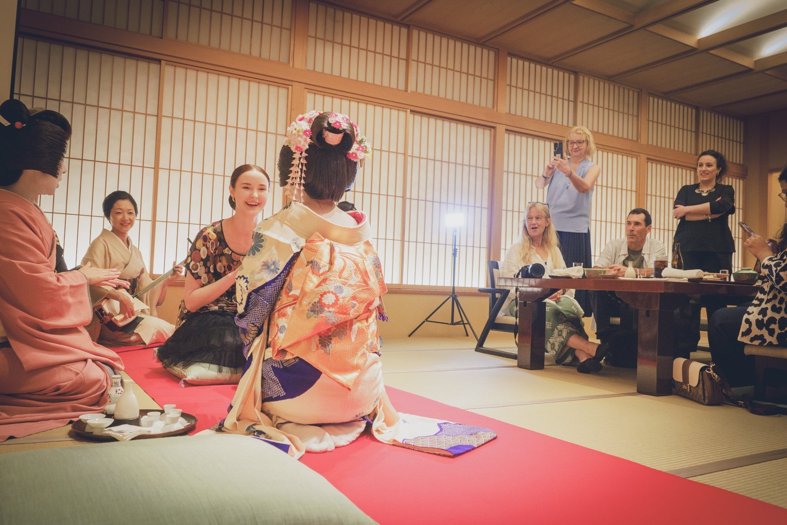 A hangyoku leading a circle of guests through an ozashiki game as the whole tatami room joins in