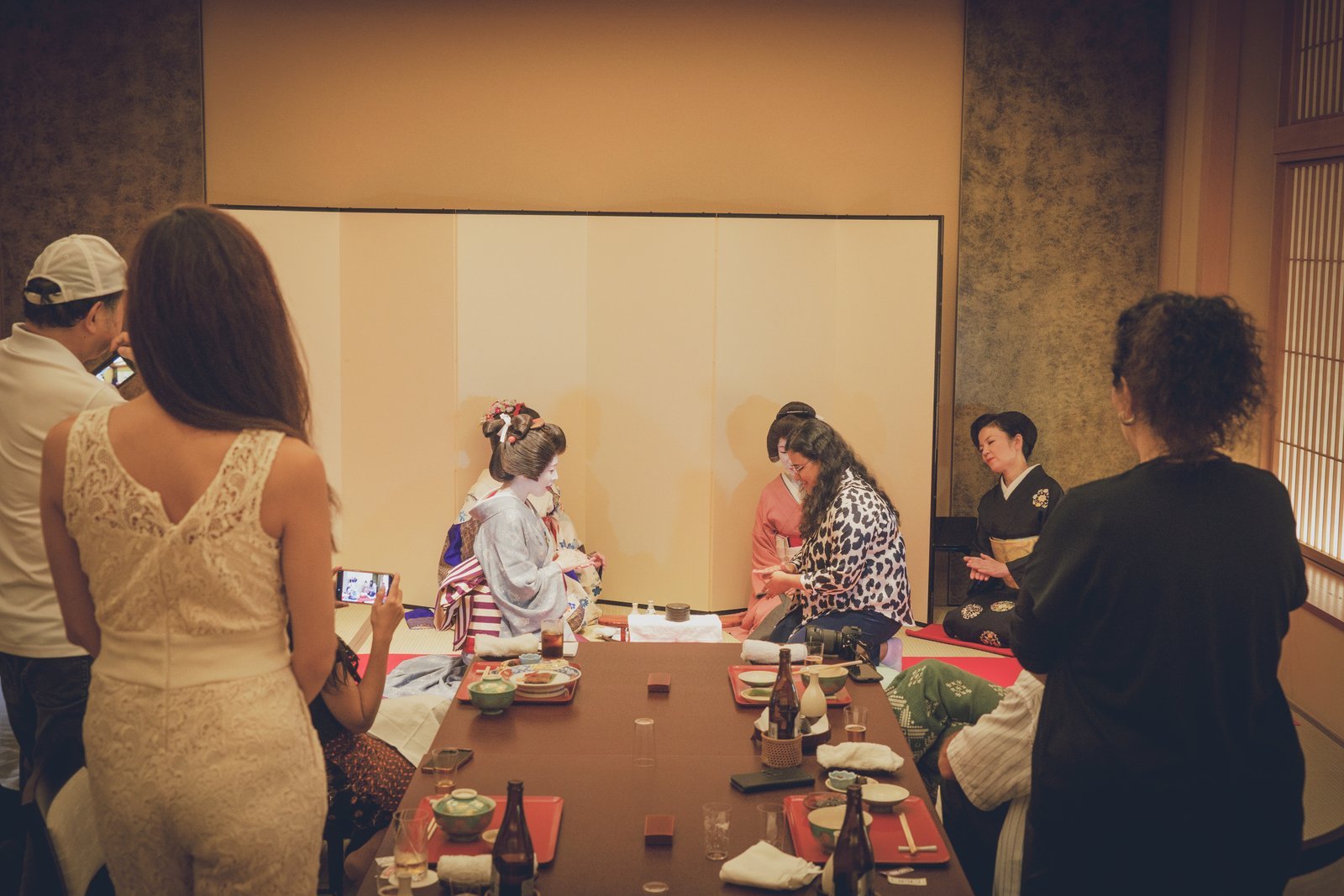 A hangyoku serving a bowl of freshly whisked matcha to a guest at Miyakodori, a seasonal sweet on the table
