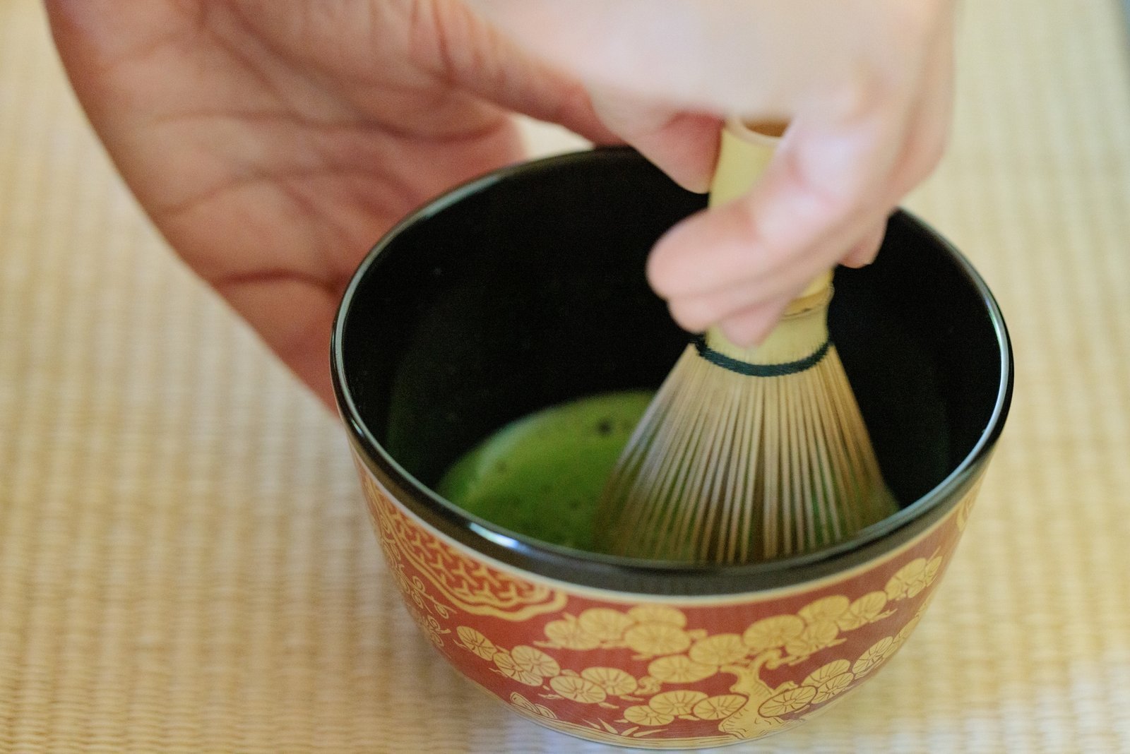 A chasen bamboo whisk working matcha into a fine froth, the tea that gives wagashi its purpose