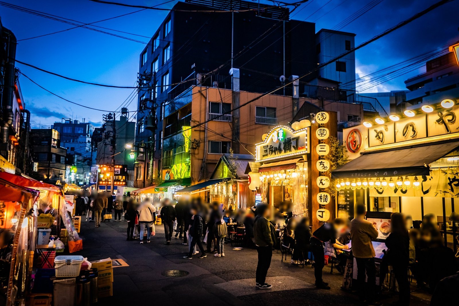 Hoppy Street at night, lined with red lanterns and signs and busy with passersby